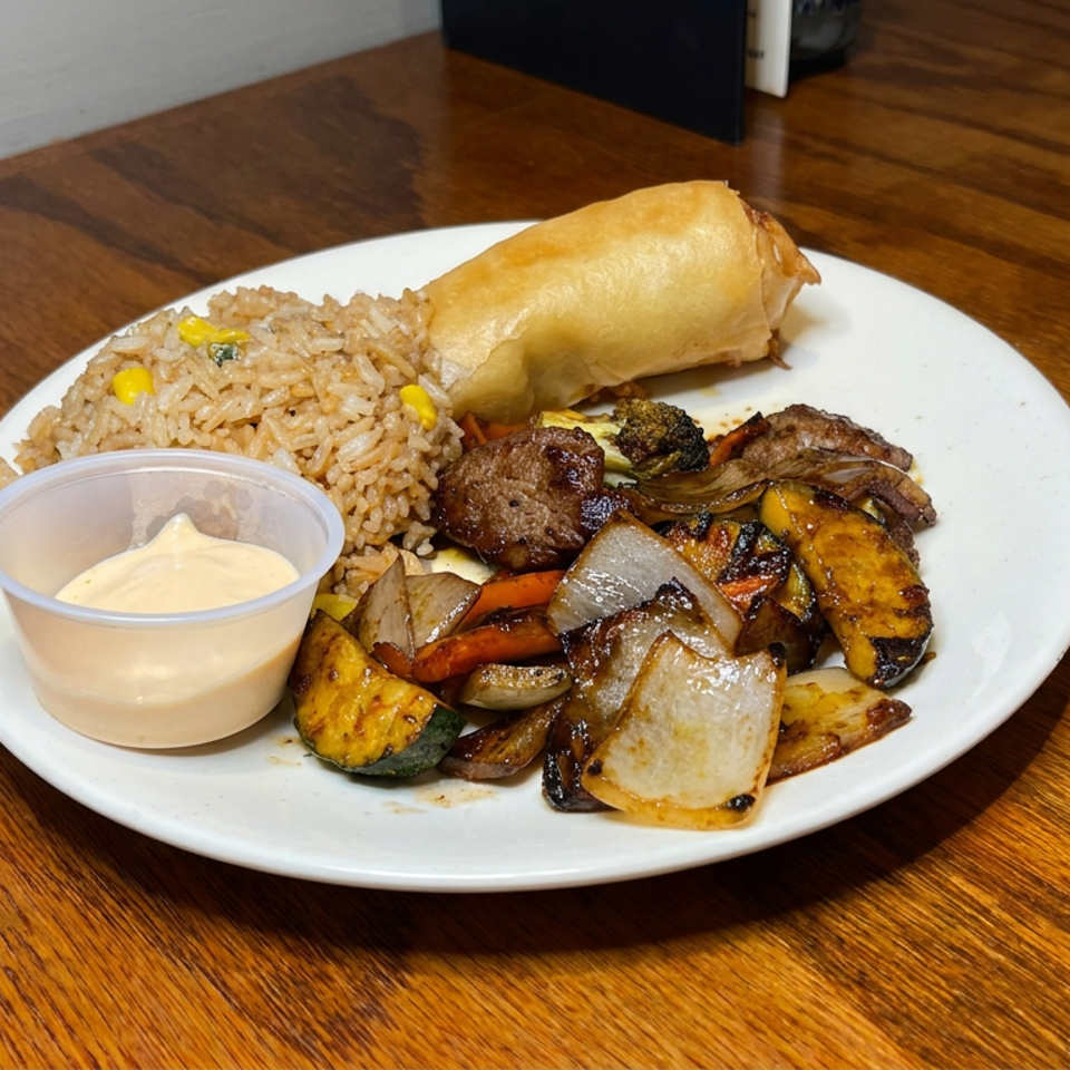 Plate of fried rice, egg roll, grilled meat and vegetables with dipping sauce on a wooden restaurant table.